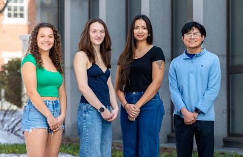 Four students standing in front of building